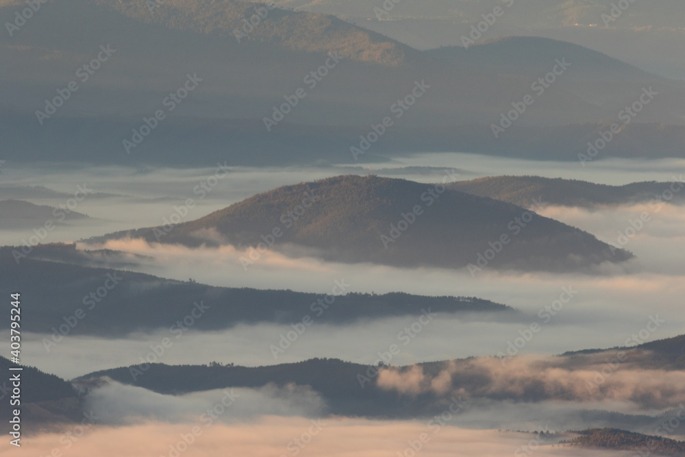 Winter in the Mountains. Beautiful orange mist or fog at sunrise time. Good sunlight and patterns in the landscape. Sea of clouds.