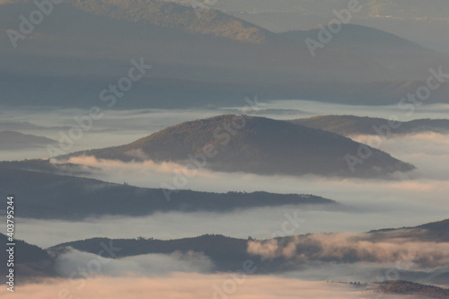 Winter in the Mountains. Beautiful orange mist or fog at sunrise time. Good sunlight and patterns in the landscape. Sea of clouds.