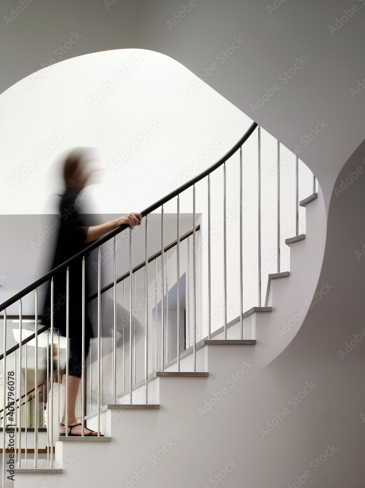 Woman walking up staircase holding handrail Woman walking up staircase holding handrail