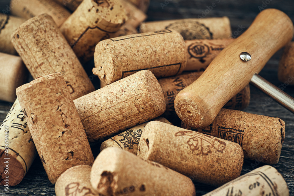 A closeup of many wine corks and a classic corkscrew