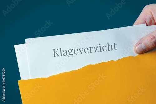 Klageverzicht. Briefumschlag wird geöffnet. Hand entnimmt Unterlagen. Text auf Post-Brief. photo