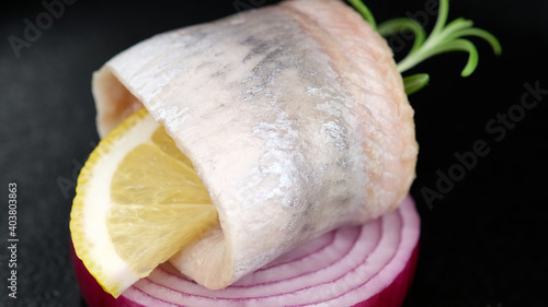 marinated herring fillet with onion on black plate