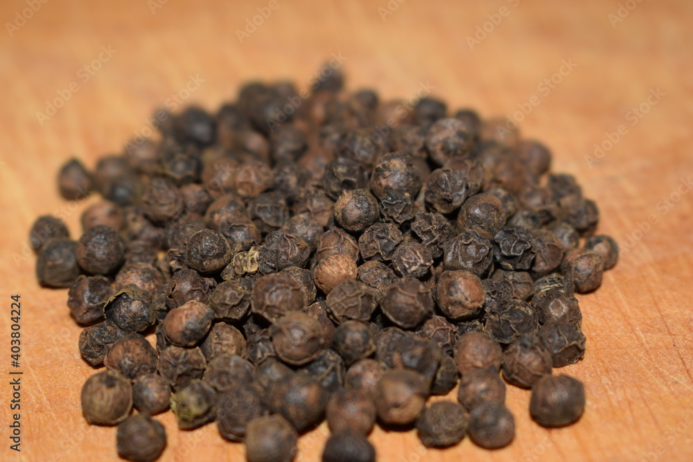 Black pepper grains close up over wooden table Black pepper grains close up over wooden table