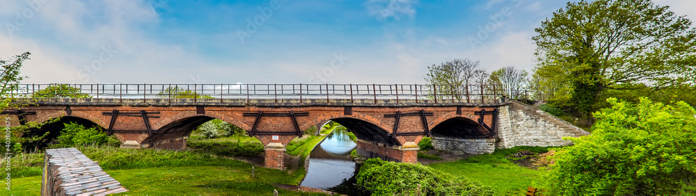 Obraz premium A panorama view of the Chesterfield canal and the Manton railway viaduct on the outskirts of Worksop, Nottinghamshire, UK in springtime
