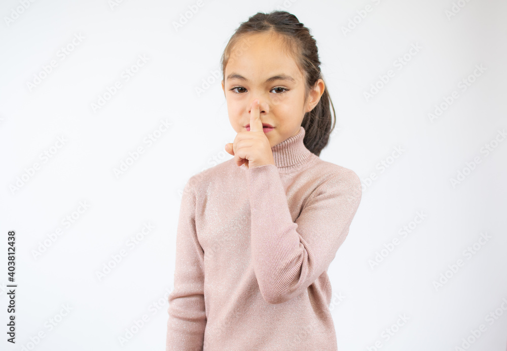 Keep Silence Concept. Cheerful child putting finger on lips, copy space, white studio wall Keep Silence Concept. Cheerful child putting finger on lips, copy space, white studio wall