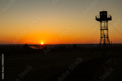 Beautiful scenery, a dawn on the state border, the silhouette of an observation tower against the background of the rising sun