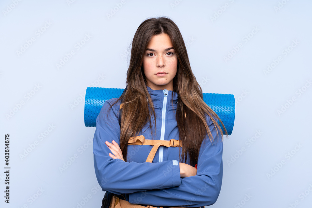 Teenager hiker girl over isolated background keeping arms crossed Teenager hiker girl over isolated background keeping arms crossed