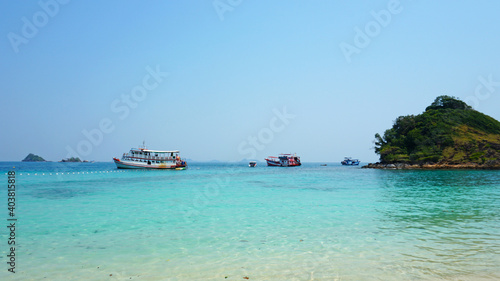 Archipelago of Islands, blue water and ships. Clear ocean water, green hills of the island, real tropical jungle. Paradise on an island in Thailand. White sand, blue sky. People are kayaking.