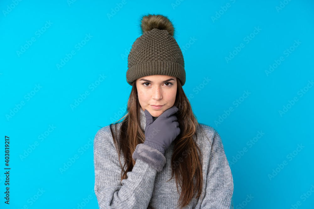 Teenager girl with winter hat over isolated blue background thinking an idea Teenager girl with winter hat over isolated blue background thinking an idea