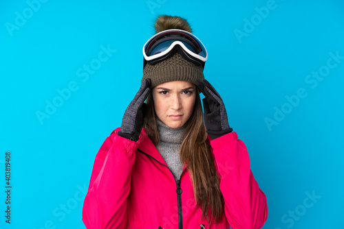 Teenager skier girl with snowboarding glasses over isolated blue background unhappy and frustrated with something. Negative facial expression © luismolinero