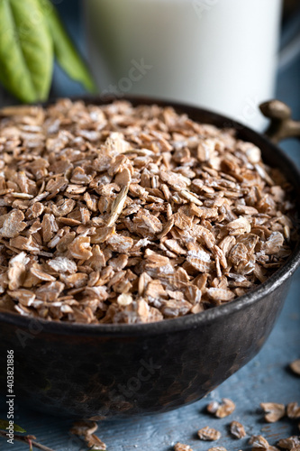 Healthy cereal flakes in a ceramic bowl. Rye flakes in a bowl on stone blue wooden background.