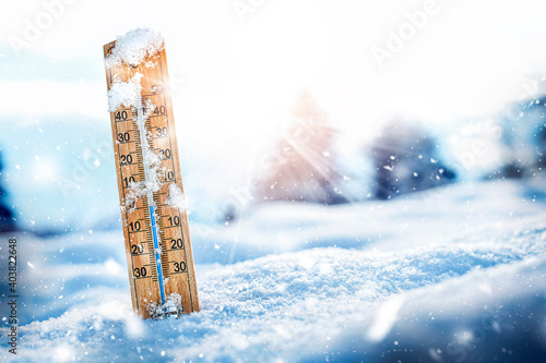 Thermometer in snow with sun backlight, show low temperatures at celsius or farenheit degree. photo