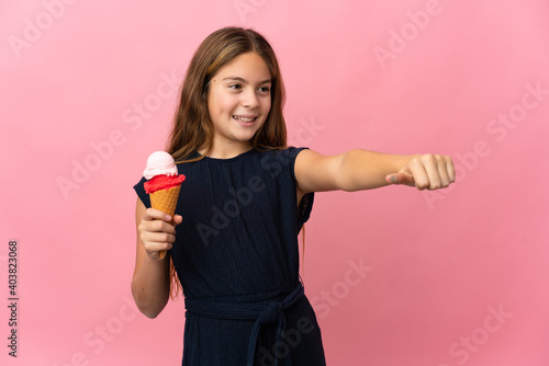 Child with a cornet ice cream over isolated pink background giving a thumbs up gesture