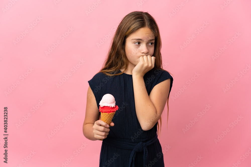 Child with a cornet ice cream over isolated pink background having doubts Child with a cornet ice cream over isolated pink background having doubts