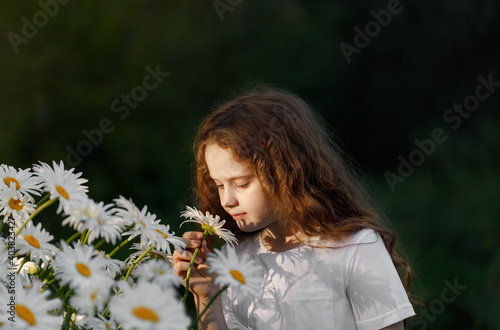 Cute girl shelling daisy flower.