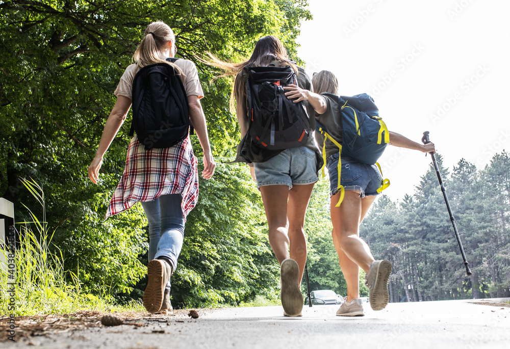Group of female friends hiking in nature.They walking by the old road  and joying in fresh air.	