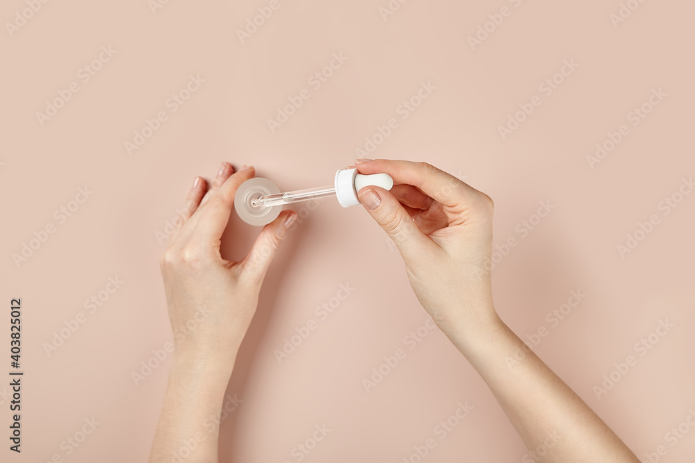 a bottle of serum in hand on a beige background a bottle of serum in hand on a beige background