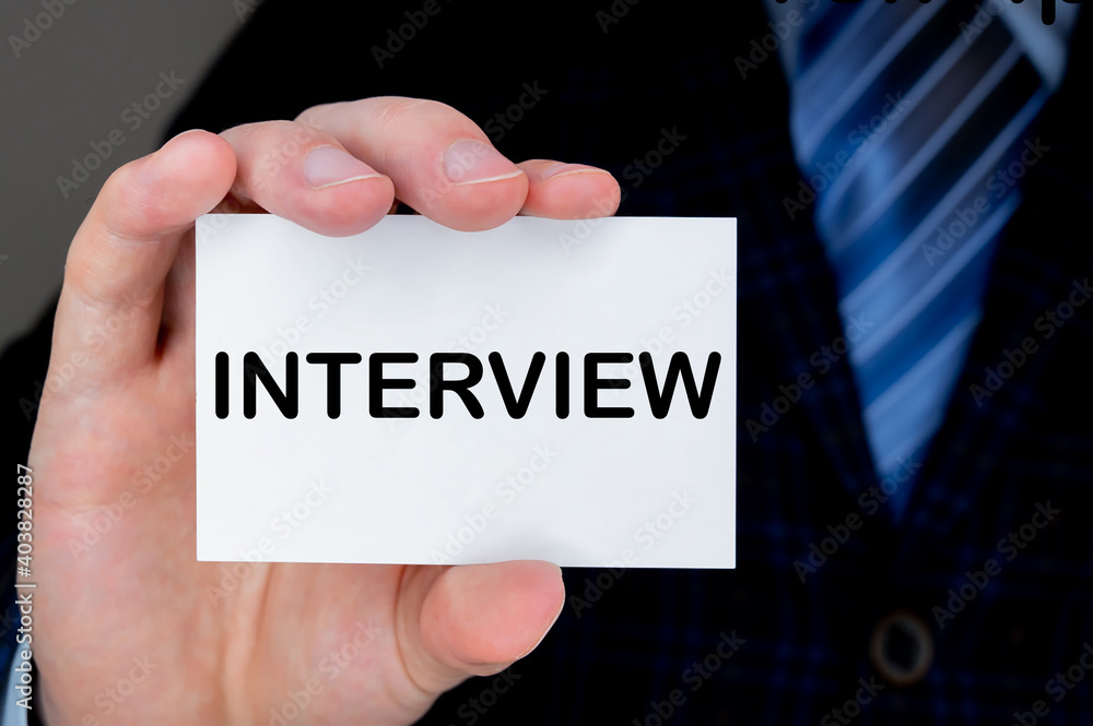 Business man handing a business card with INTERVIEW text on it. Business and finances concept. Business man handing a business card with INTERVIEW text on it. Business and finances concept.