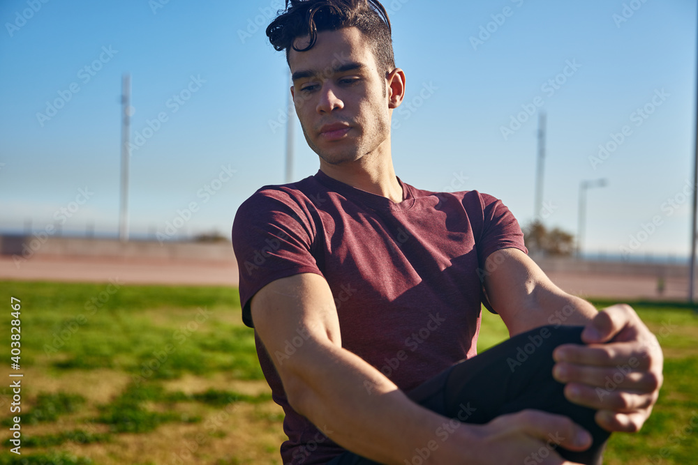 Man looks to side as he holds knee up