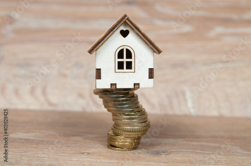 wooden house on a stack of coins folded crookedly, real estate insurance concept photo