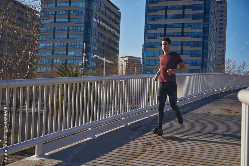 Man running along a bridge past tall buildings
