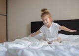 Little girl have fun on the bed, laughing and playful.