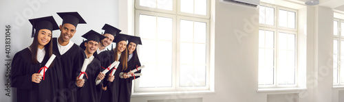 Window of opportunity. Hope for the best future. Happy smiling diverse academy graduates holding diploma scrolls. International university students in gowns and caps celebrating graduation. Web banner