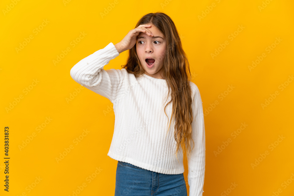 Child over isolated yellow background doing surprise gesture while looking to the side Child over isolated yellow background doing surprise gesture while looking to the side