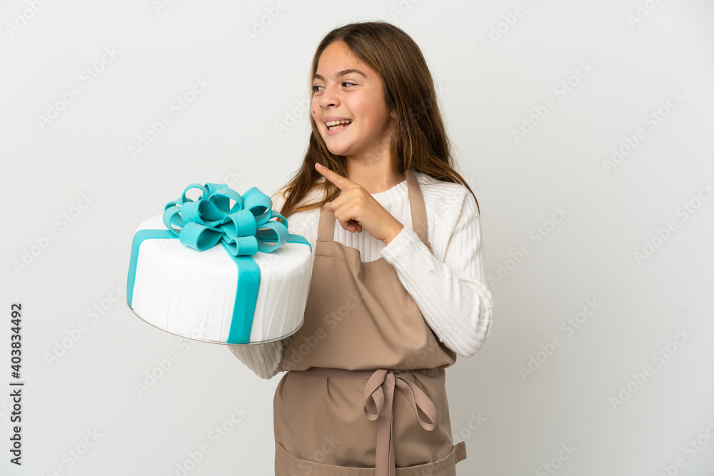 Little girl holding a big cake over isolated white background intending to realizes the solution while lifting a finger up Little girl holding a big cake over isolated white background intending to realizes the solution while lifting a finger up