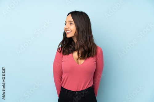 Young mixed race woman isolated on blue background looking side