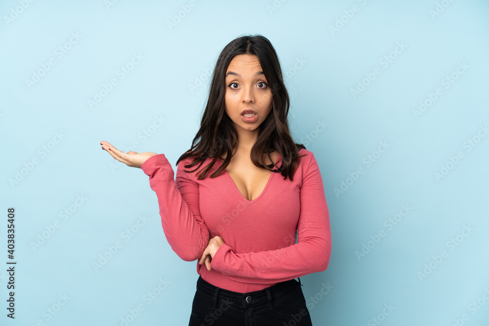 Young mixed race woman isolated on blue background making doubts gesture Young mixed race woman isolated on blue background making doubts gesture