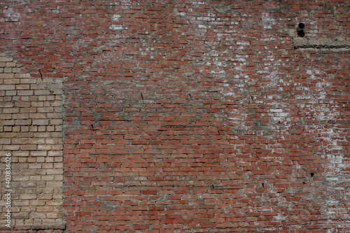 Red brick wall with a white brick outline of another house.