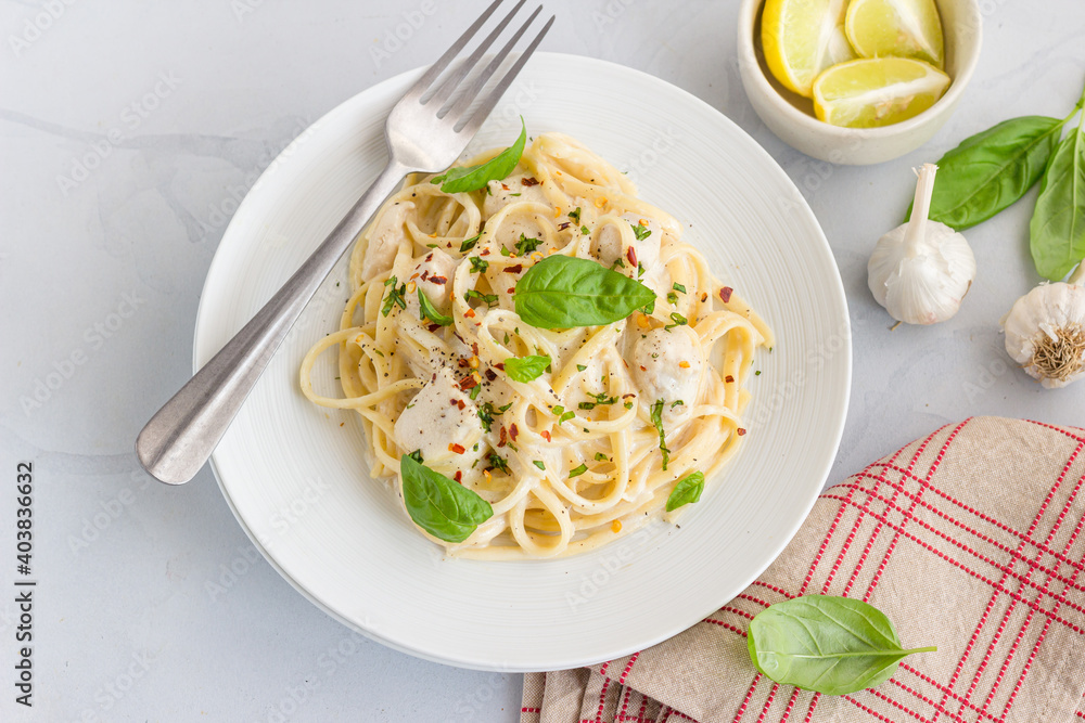 Linguine Pasta in White Sauce Garnished with Basil and Lemon on White Background, Italian Food Photography