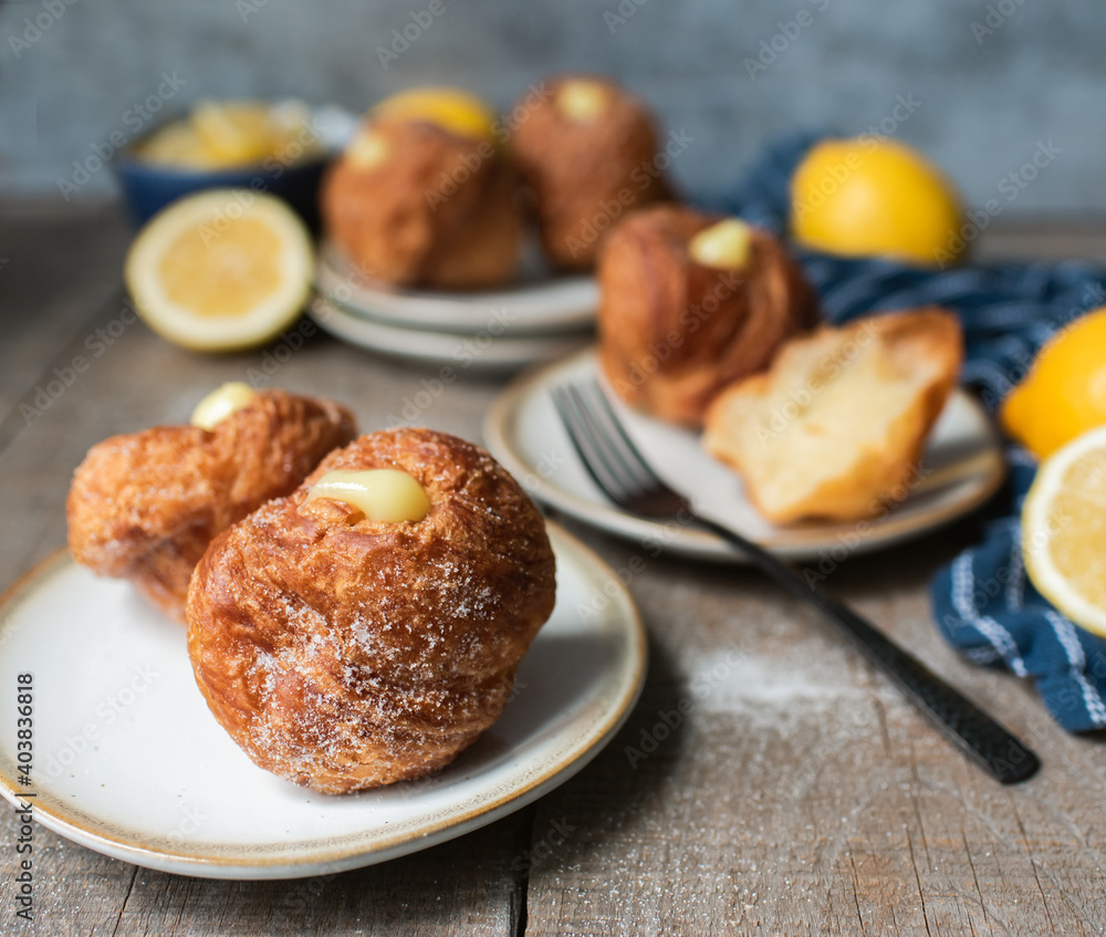 Lemon filled cruffins on wooden table with plates and forks. Lemon filled cruffins on wooden table with plates and forks.