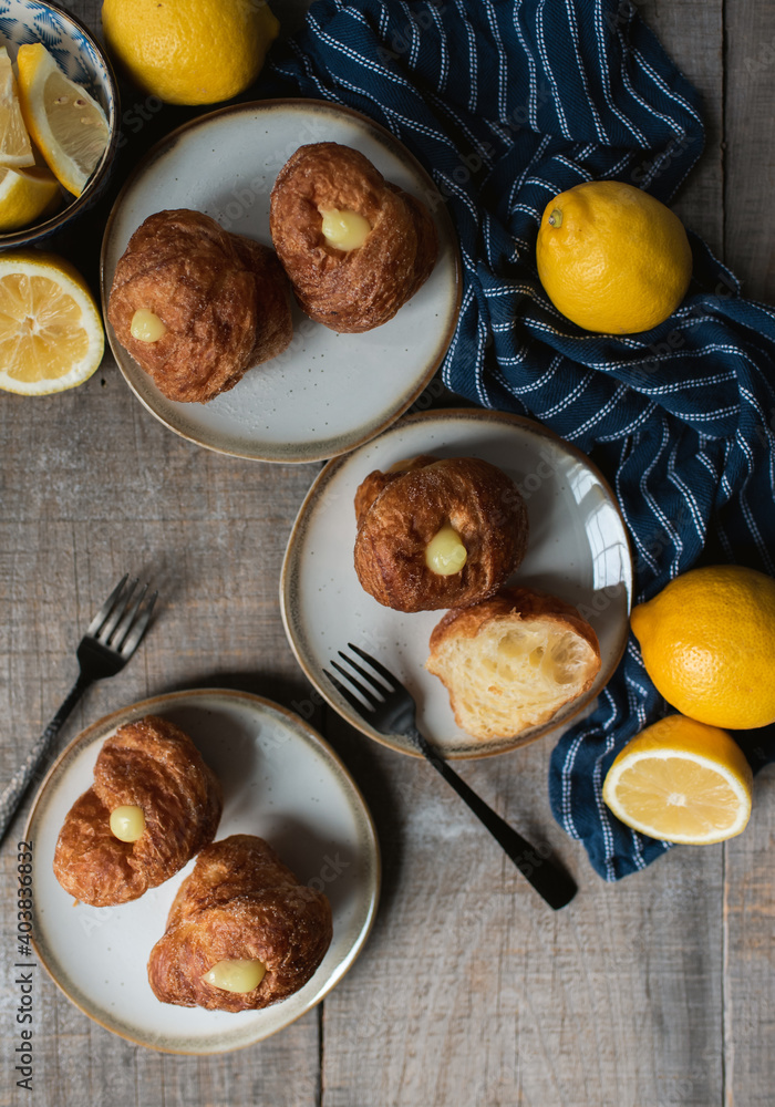 Overhead of lemon filled cruffins on wood table with plates and forks. Overhead of lemon filled cruffins on wood table with plates and forks.
