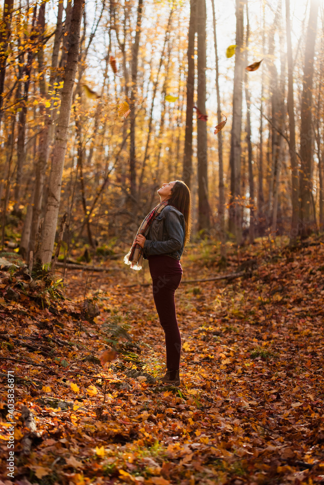 Woman standing in a forest looking up at the trees on an autumn day. Woman standing in a forest looking up at the trees on an autumn day.