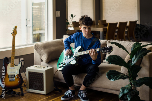 Young male musician playing electric guitar at home photo