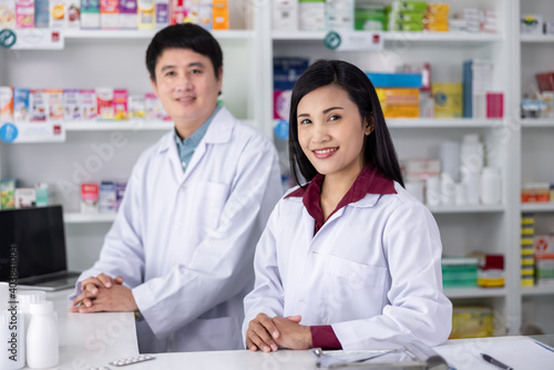 Two Male and female pharmacists smiling happy to Service in drugstore Thailand health care and business concept