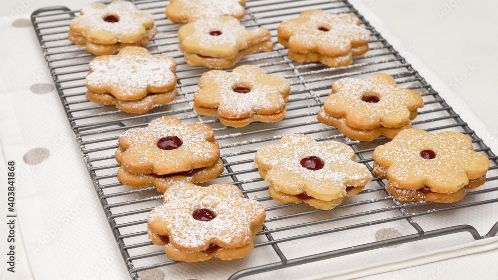 Flower shaped shortbread cookies filled with raspberry jam. Fresh baked cookies close up on cooling rack Flower shaped shortbread cookies filled with raspberry jam. Fresh baked cookies close up on cooling rack