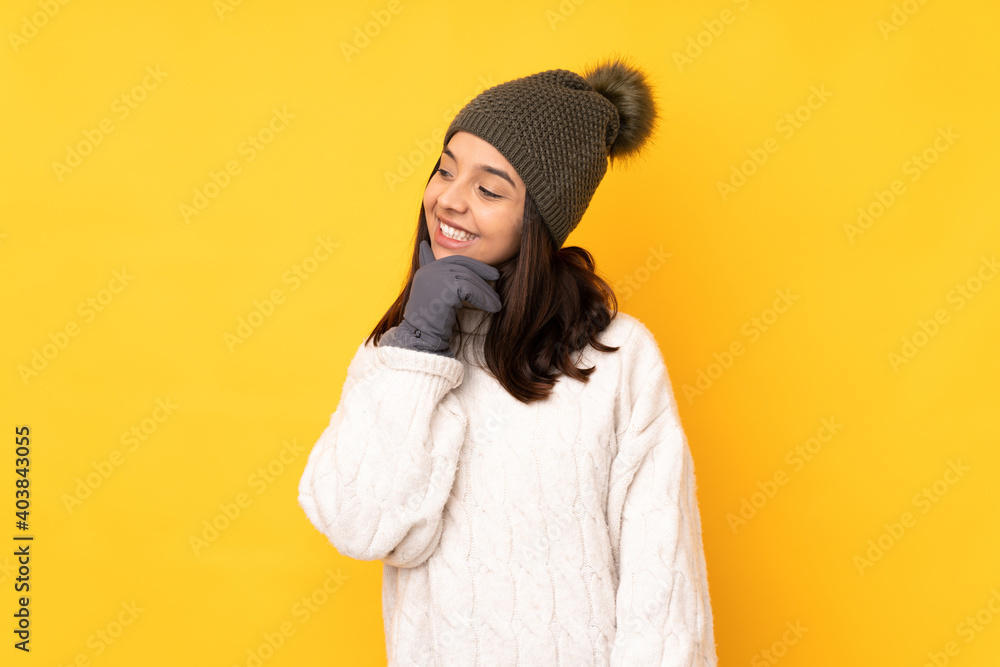 Young woman with winter hat over isolated yellow background looking to the side Young woman with winter hat over isolated yellow background looking to the side