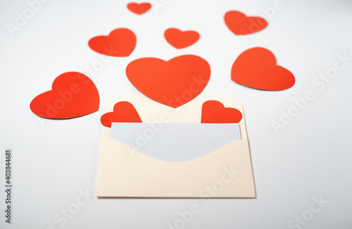 Envelope with a blank sheet and red paper hearts on the light (white) background. Flat lay, top view. Romantic love letter for Valentine's day concept. © lmot11