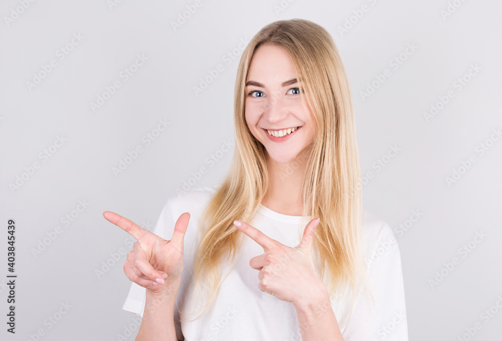 Portrait of a pretty girl pointing finger away isolated on a gray background Portrait of a pretty girl pointing finger away isolated on a gray background