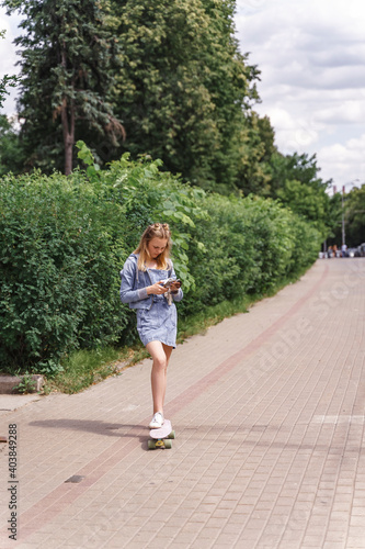 teen girl with skateboard and mobile phone in the park