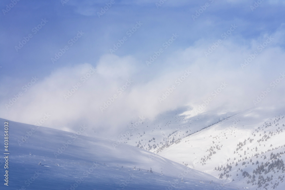 Plakat Clouds covering the snowy mountains. Winter landscape.