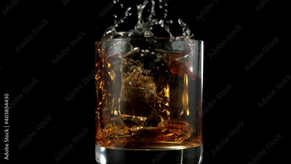 Super slow motion of falling ice cube into whiskey drink. Filmed on high speed cinema camera, 1000 fps. Super slow motion of falling ice cube into whiskey drink. Filmed on high speed cinema camera, 1000 fps.