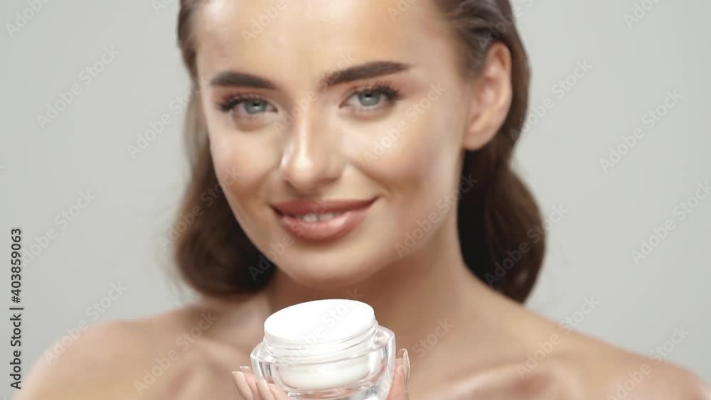 pretty girl holding cream and applying it on her face pretty girl holding cream and applying it on her face