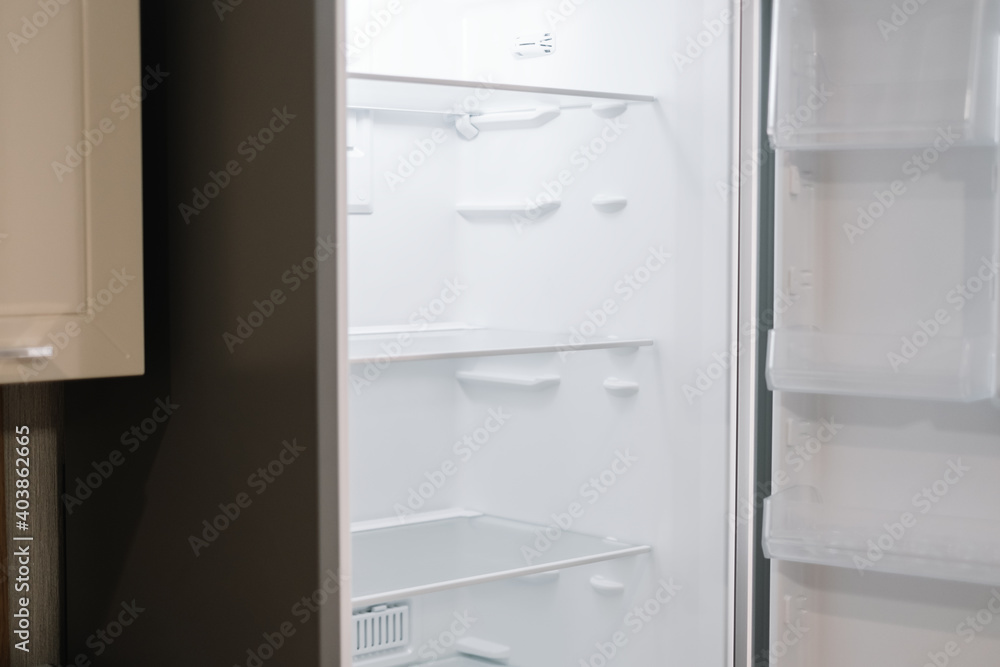 Fototapeta premium Empty open white refrigerator in the kitchen.