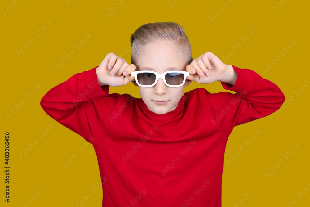 a cool child in a red jacket holds his hands to his glasses on a yellow backgroun a cool child in a red jacket holds his hands to his glasses on a yellow backgroun