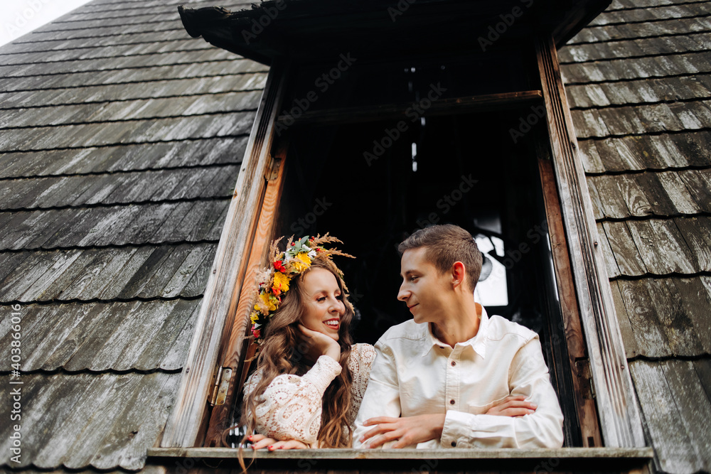 Young couple standing near the window in a wooden house in the middle of the lake.
