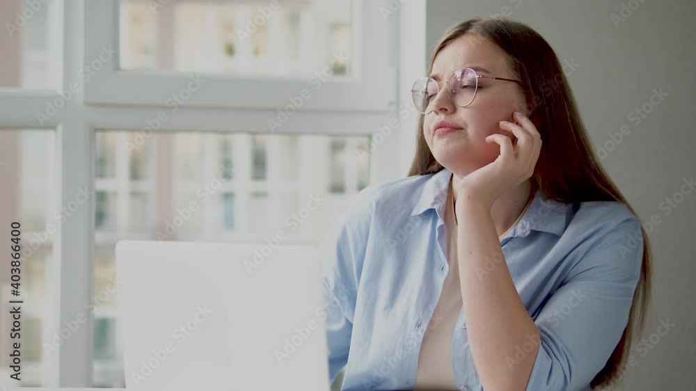 Sad unhappy young woman working on laptop at home office, concentration problems Sad unhappy young woman working on laptop at home office, concentration problems